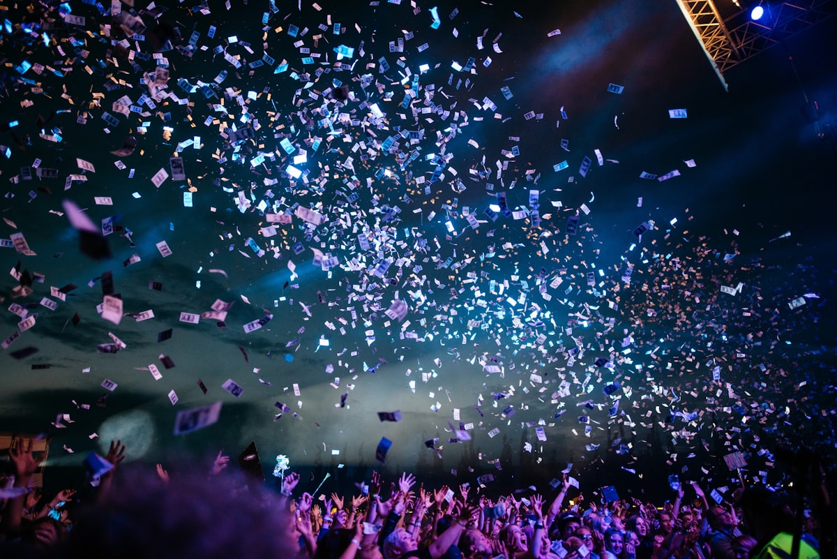 Confetti raining over a concert crowd in blue light