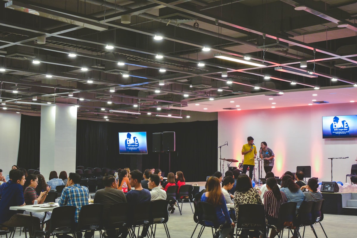 Speakers on stage in front of a seated audience at a live event